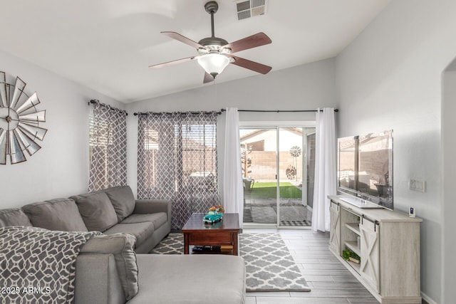 living room featuring vaulted ceiling, wood finished floors, visible vents, and a ceiling fan