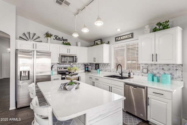 kitchen featuring stainless steel appliances, visible vents, white cabinets, vaulted ceiling, and a sink