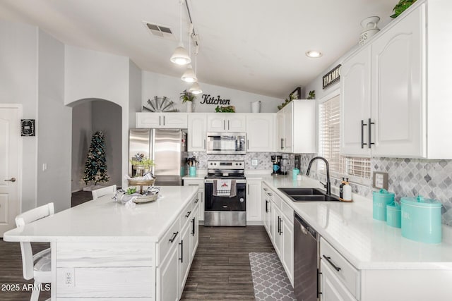 kitchen featuring stainless steel appliances, a sink, visible vents, white cabinetry, and vaulted ceiling