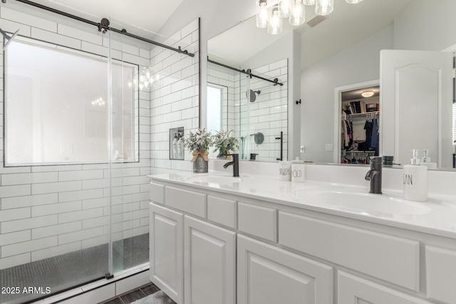 bathroom featuring lofted ceiling, a stall shower, a spacious closet, and a sink