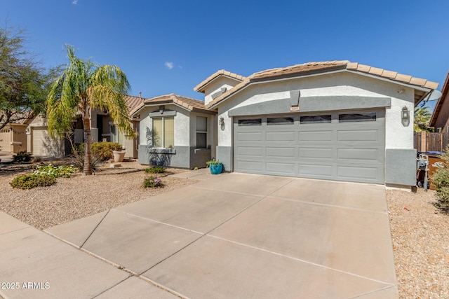 view of front facade featuring concrete driveway, a tile roof, an attached garage, and stucco siding