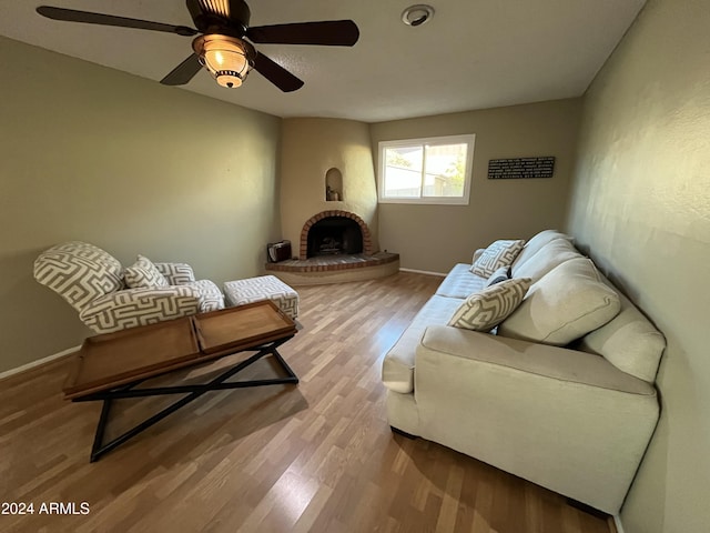 living room with a fireplace, light hardwood / wood-style flooring, and ceiling fan