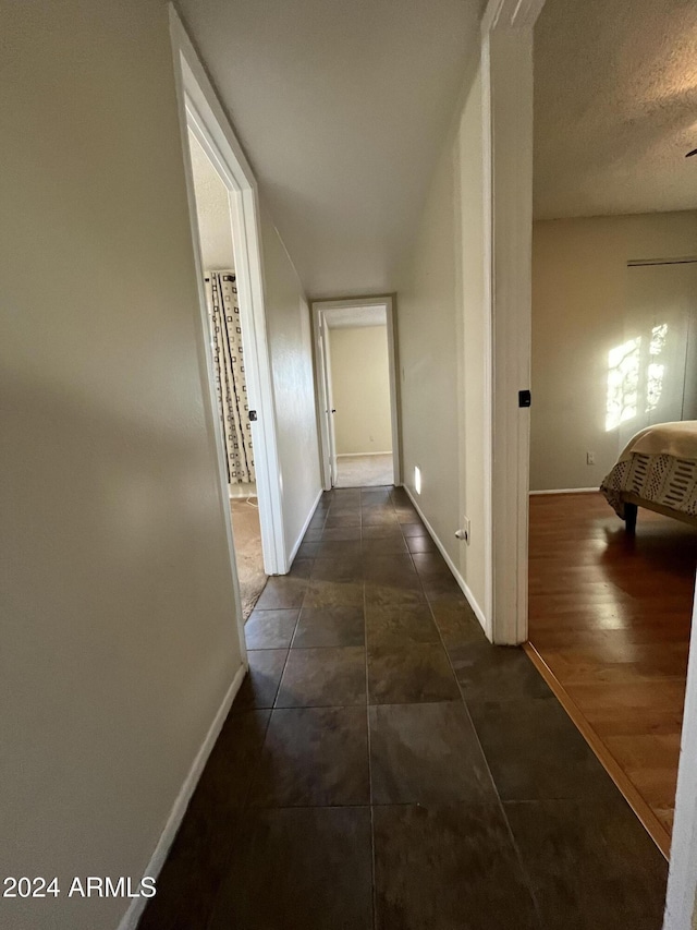 hallway with a textured ceiling and dark hardwood / wood-style floors