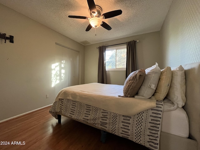 bedroom with hardwood / wood-style flooring, ceiling fan, a textured ceiling, and a closet