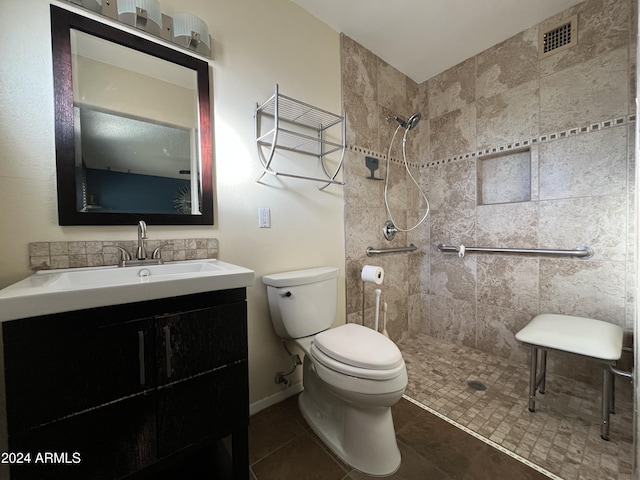 bathroom with tile patterned floors, vanity, toilet, and tiled shower