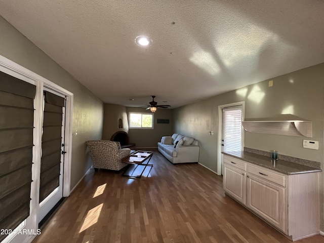 living room featuring ceiling fan, dark hardwood / wood-style flooring, and a textured ceiling