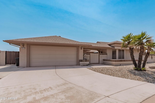 view of front facade featuring stucco siding, concrete driveway, a garage, and fence