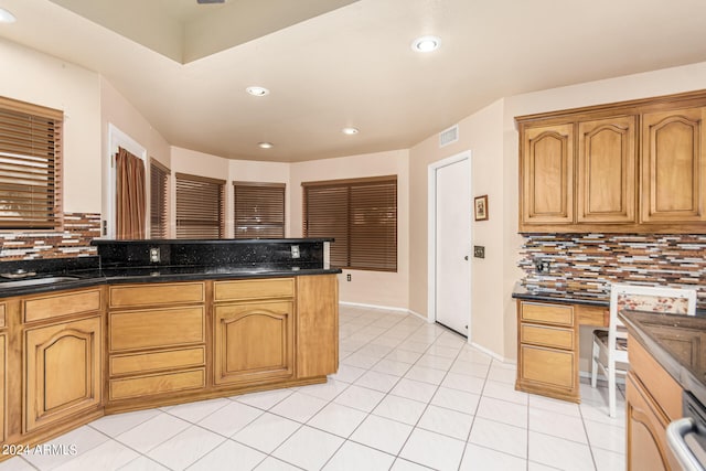 kitchen with sink, dark stone countertops, light tile patterned floors, and tasteful backsplash