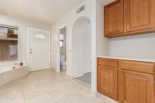 entryway featuring light tile patterned floors, visible vents, arched walkways, and baseboards