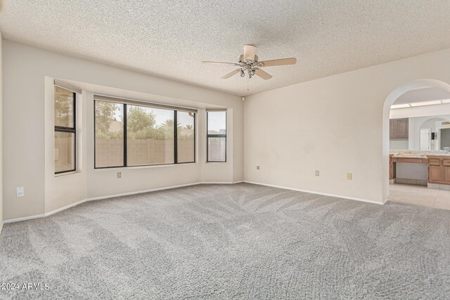 carpeted spare room featuring a textured ceiling and ceiling fan