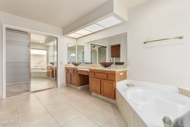 bathroom featuring a relaxing tiled tub, tile patterned flooring, and vanity