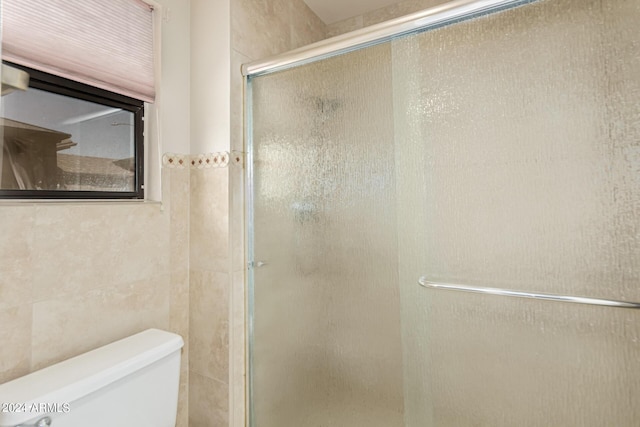 full bath featuring tile walls, toilet, and a stall shower