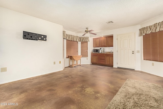 interior space featuring visible vents, brown cabinets, stainless steel microwave, a textured ceiling, and light countertops