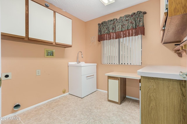 washroom with electric dryer hookup, a sink, a textured ceiling, cabinet space, and baseboards