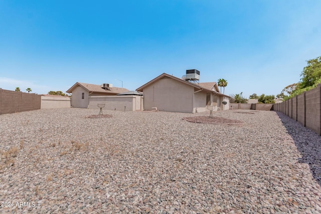 rear view of property featuring stucco siding, central AC, and a fenced backyard