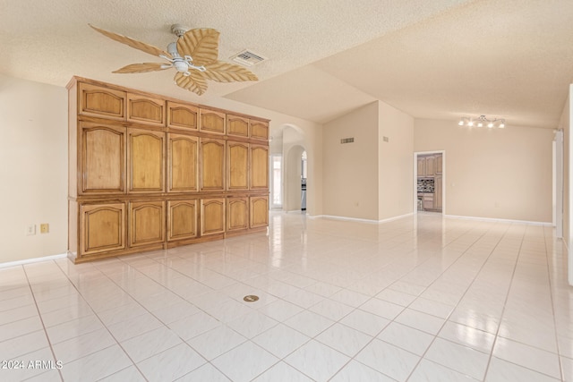 unfurnished room featuring vaulted ceiling, rail lighting, light tile patterned floors, and a textured ceiling