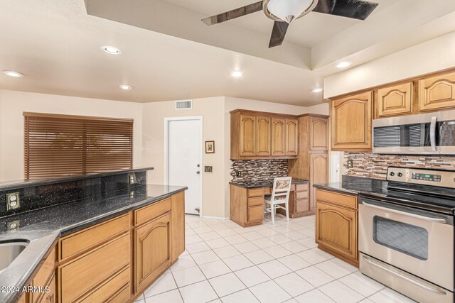 kitchen featuring tasteful backsplash, stainless steel appliances, light tile patterned floors, dark stone countertops, and ceiling fan