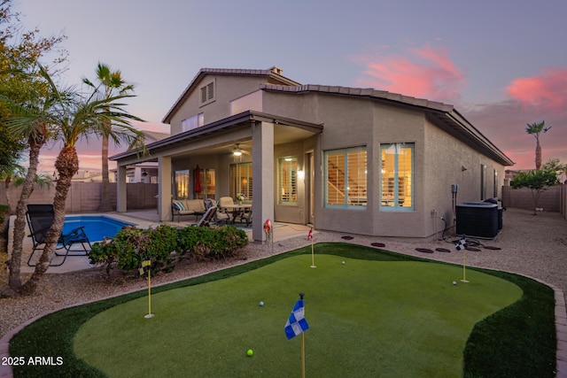 back house at dusk featuring a patio, a fenced in pool, central AC, and ceiling fan