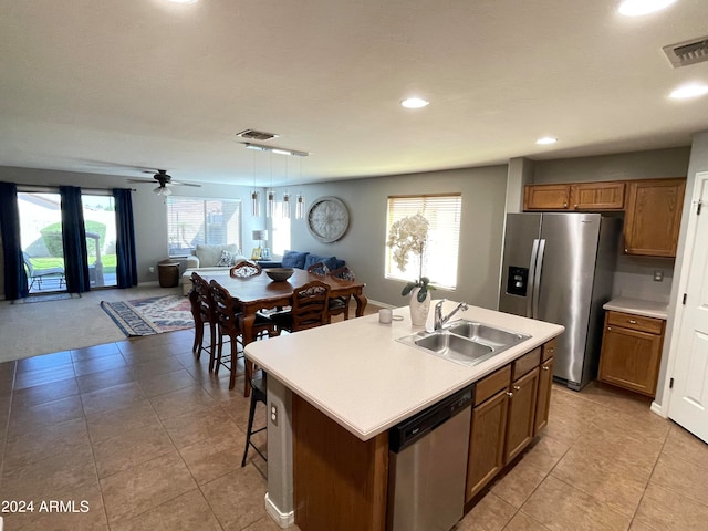 kitchen featuring plenty of natural light, stainless steel appliances, a kitchen island with sink, sink, and hanging light fixtures