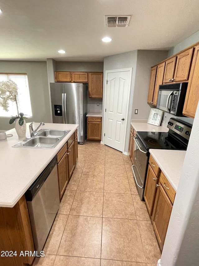 kitchen with appliances with stainless steel finishes, light tile patterned floors, and sink