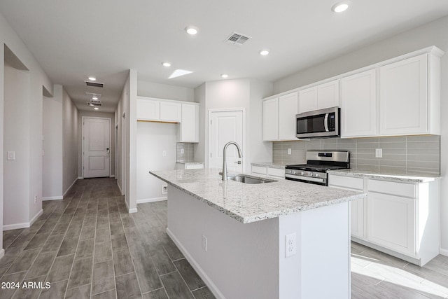 kitchen featuring tasteful backsplash, a kitchen island with sink, sink, and appliances with stainless steel finishes