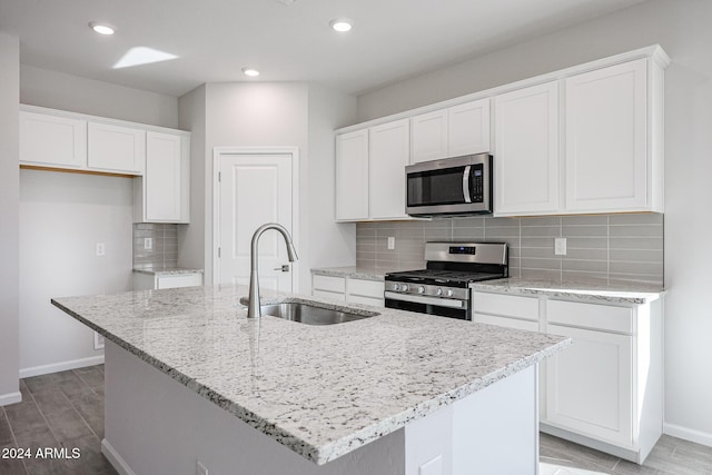 kitchen featuring white cabinets, sink, stainless steel appliances, and a kitchen island with sink