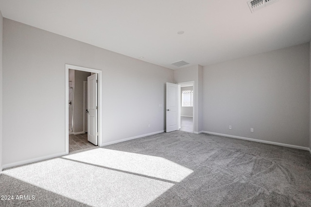 unfurnished bedroom with ensuite bathroom and light carpet