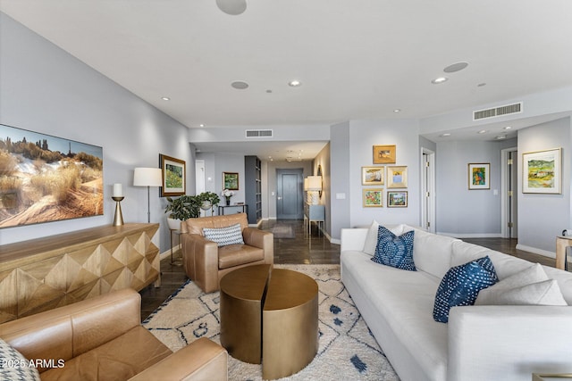 living room featuring visible vents, baseboards, and wood finished floors