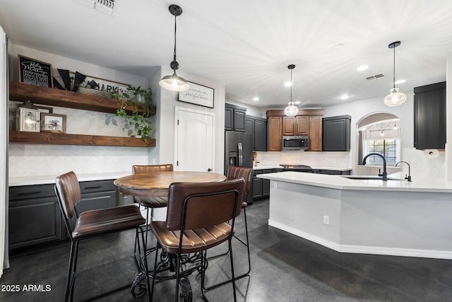 kitchen with tasteful backsplash, sink, stainless steel appliances, and hanging light fixtures