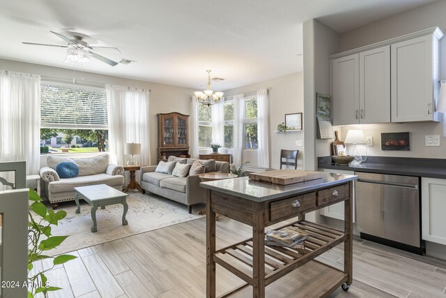 kitchen with a wealth of natural light, dishwasher, ceiling fan with notable chandelier, and light hardwood / wood-style flooring