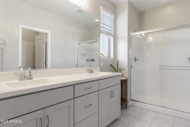 full bath featuring double vanity, a shower stall, a sink, and tile patterned floors