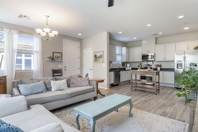 living area with light wood-type flooring, visible vents, plenty of natural light, and recessed lighting