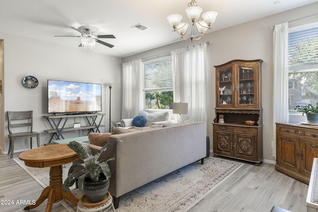 living room featuring ceiling fan with notable chandelier, plenty of natural light, and light hardwood / wood-style floors