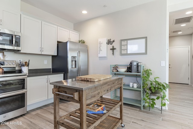 kitchen with appliances with stainless steel finishes, white cabinets, and light hardwood / wood-style floors