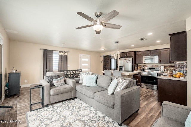 11450 E Elton Ave, Mesa, AZ 85208 - living room featuring a barn door, light wood finished floors, a ceiling fan, and recessed lighting