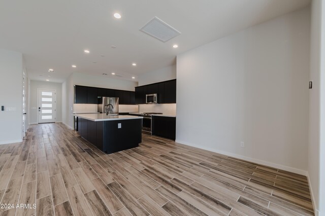 kitchen featuring appliances with stainless steel finishes, an island with sink, and light hardwood / wood-style floors