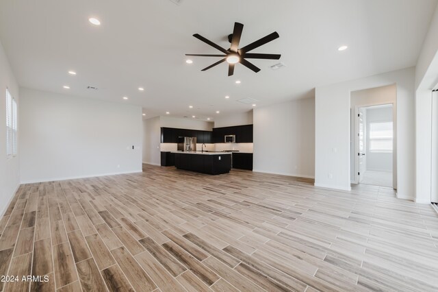 unfurnished living room featuring sink, ceiling fan, and light hardwood / wood-style floors