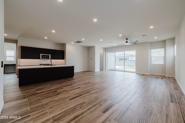 living room with ceiling fan, light wood-type flooring, and sink