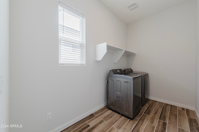 laundry room featuring washing machine and clothes dryer, plenty of natural light, and dark wood-type flooring