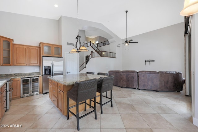 kitchen with a breakfast bar, stainless steel appliances, a center island, decorative light fixtures, and beverage cooler