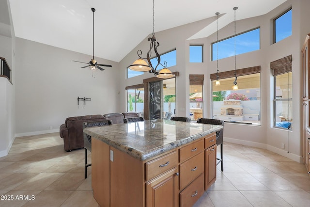 kitchen featuring pendant lighting, a breakfast bar area, a center island, and dark stone countertops