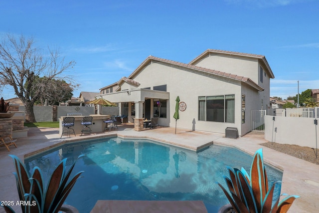 rear view of house featuring a fenced in pool, an outdoor bar, and a patio