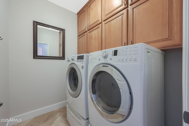 clothes washing area with cabinets, light tile patterned flooring, and washer and clothes dryer