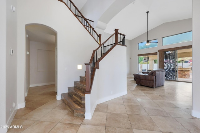 stairs featuring ceiling fan, tile patterned floors, and high vaulted ceiling