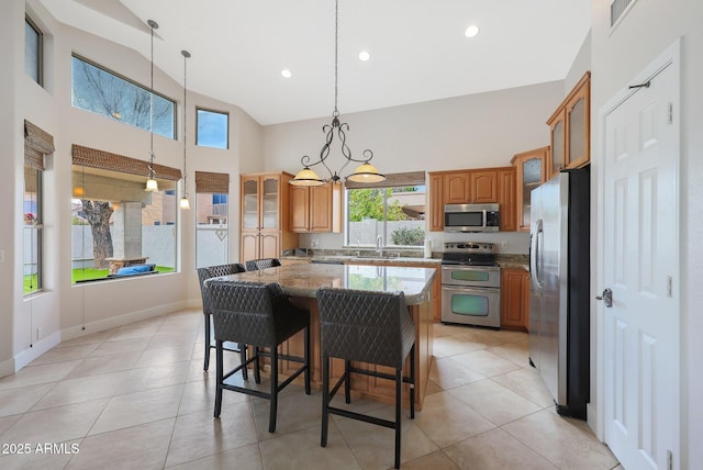 kitchen with pendant lighting, a center island, stone counters, and appliances with stainless steel finishes