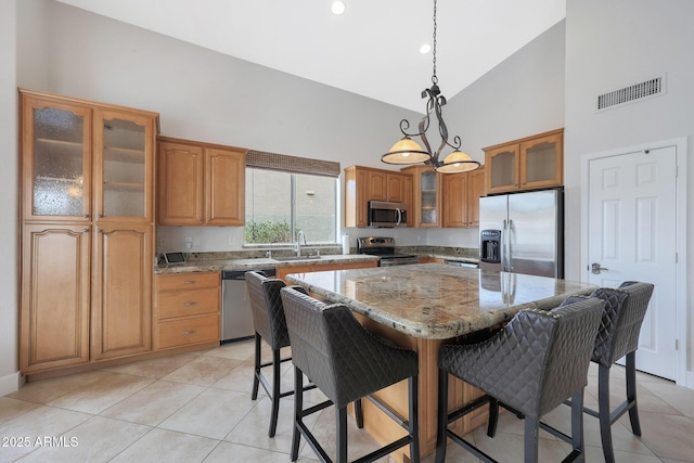 kitchen featuring pendant lighting, sink, appliances with stainless steel finishes, a center island, and light stone countertops