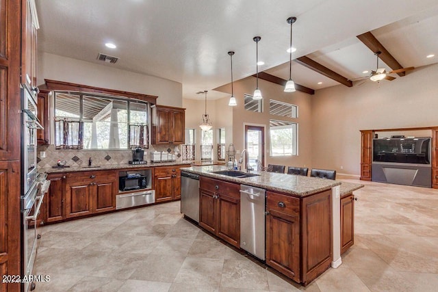 kitchen featuring beam ceiling, sink, hanging light fixtures, an island with sink, and appliances with stainless steel finishes