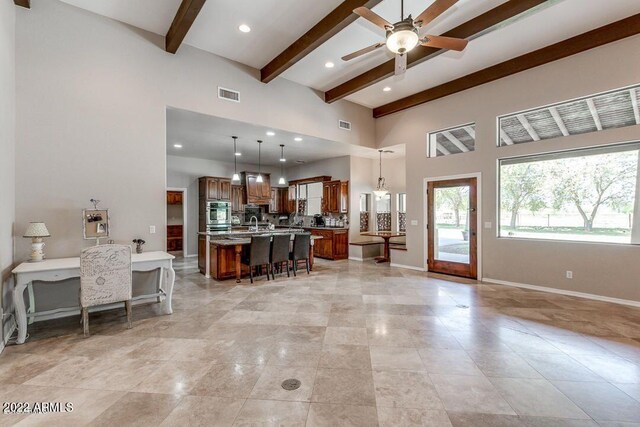 living room featuring beam ceiling, ceiling fan, and a high ceiling