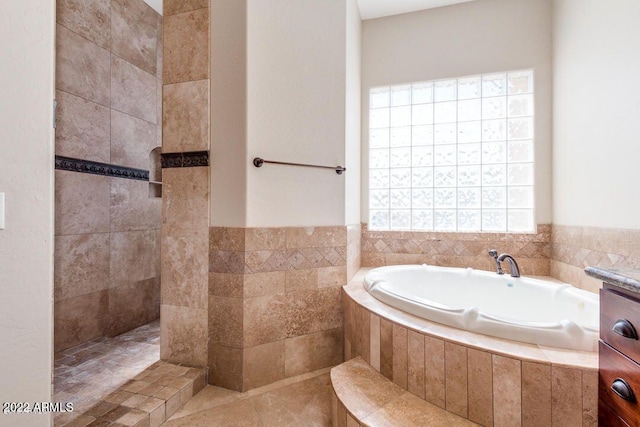 bathroom featuring tile patterned flooring, tile walls, and tiled bath