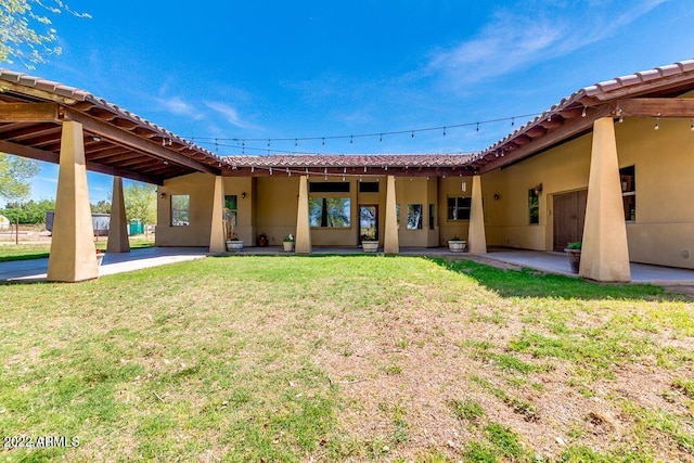 back of property with a lawn and a patio area